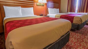 Camera d'albergo con due letti, ognuno con copripiumino rosso e beige, una testiera in legno e una lampada fissata al muro.