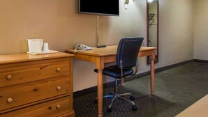 Une chambre d’hôtel avec un bureau en bois, une chaise, un téléviseur fixé au mur, un miroir et un téléphone.