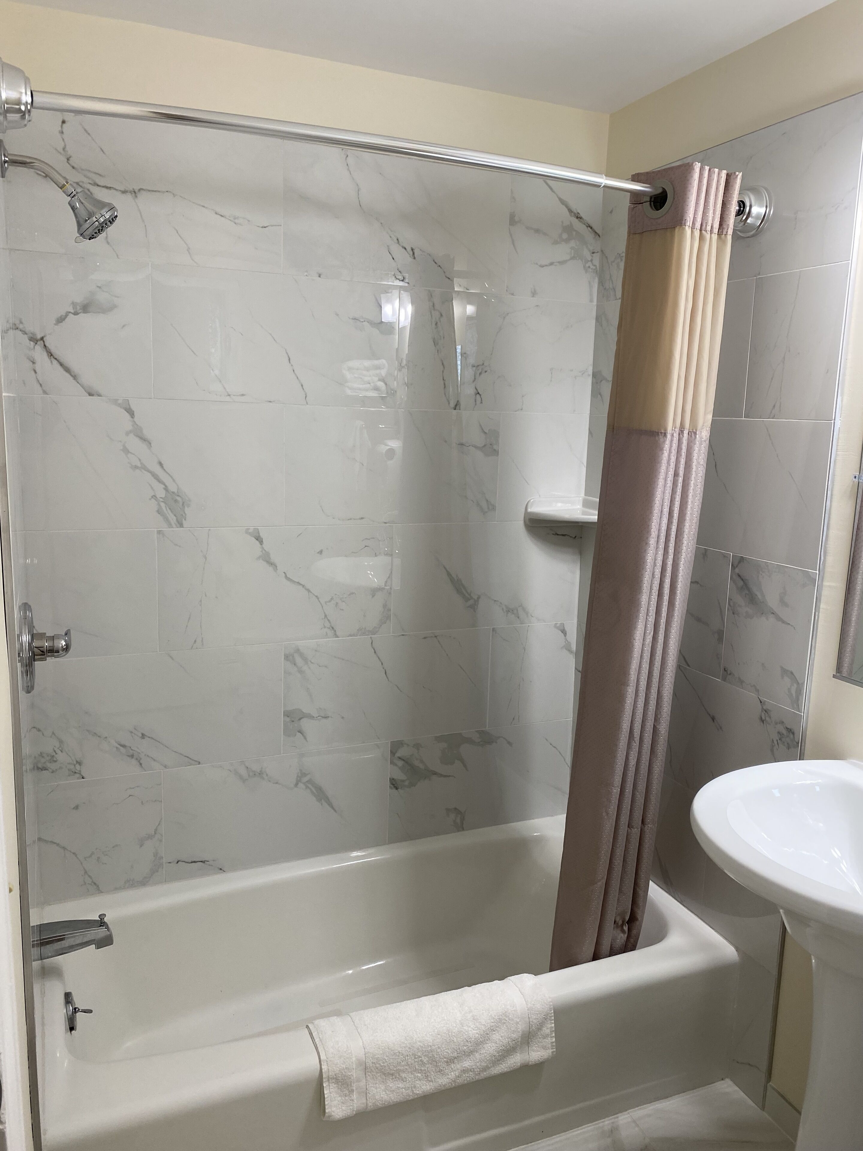 A bathroom with a glass-enclosed shower, a white bathtub, and a sink with a mirror.