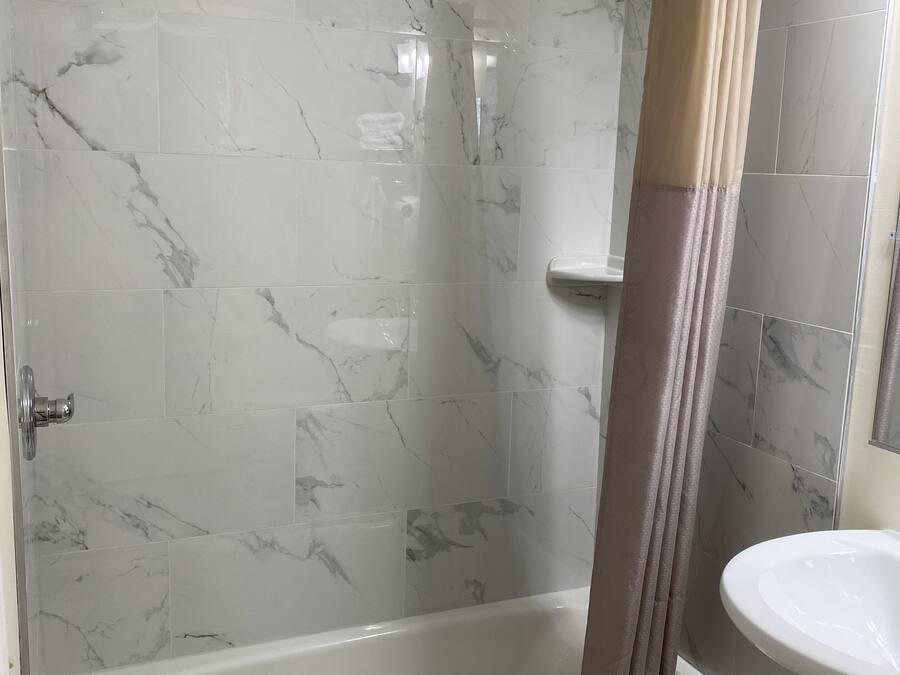 Un baño con ducha de vidrio, bañera blanca y lavamanos con espejo.