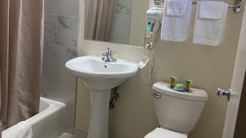 A bathroom with a pedestal sink, a toilet, a shower area, and a towel rack with towels.