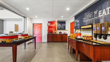 A modern kitchen area with a waffle station, a coffee machine, and a display of various food items.