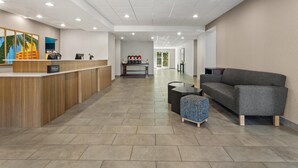 Un vestíbulo de hotel con mostrador de recepción, zona de estar y estación de café.