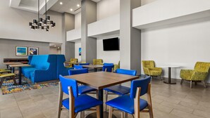 A modern dining area with blue and yellow chairs, a wooden table, and a patterned rug.
