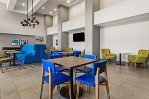 A modern dining area with blue and yellow chairs, a wooden table, and a patterned rug.