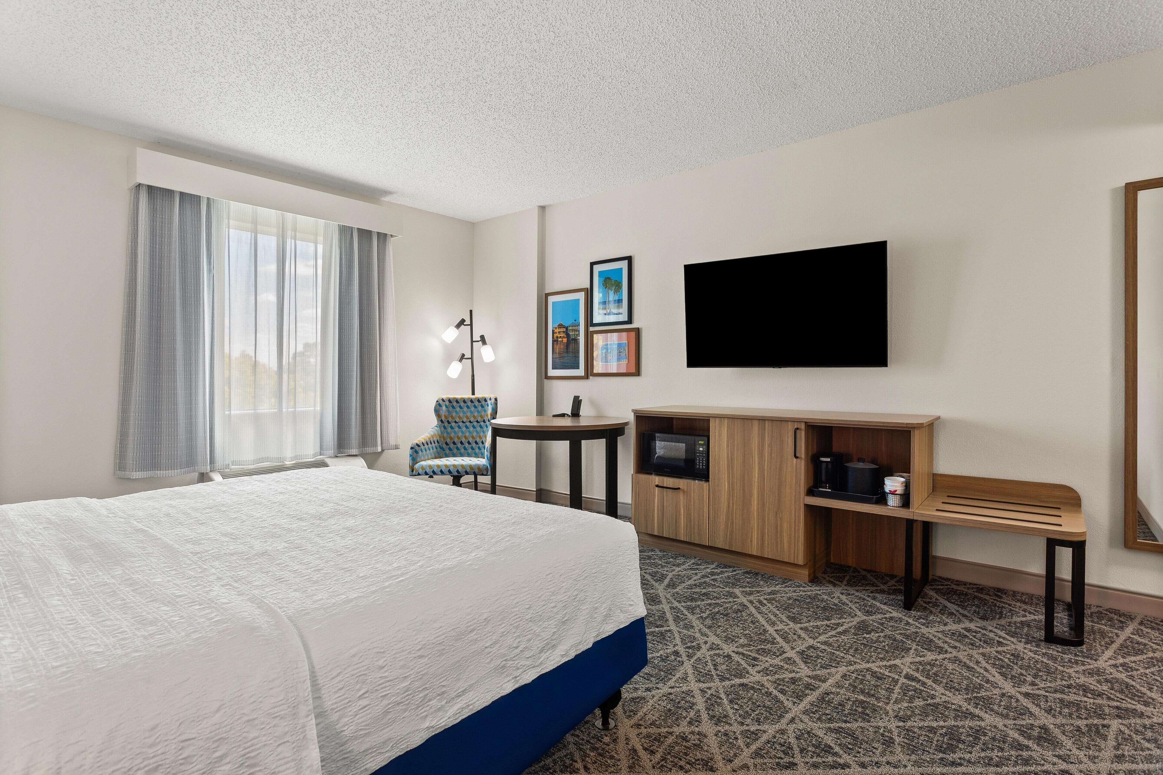 Una habitación de hotel con una cama grande, un escritorio, una silla, un televisor y un microondas.