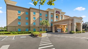 A large, beige hotel with a prominent entrance and a parking lot in front.