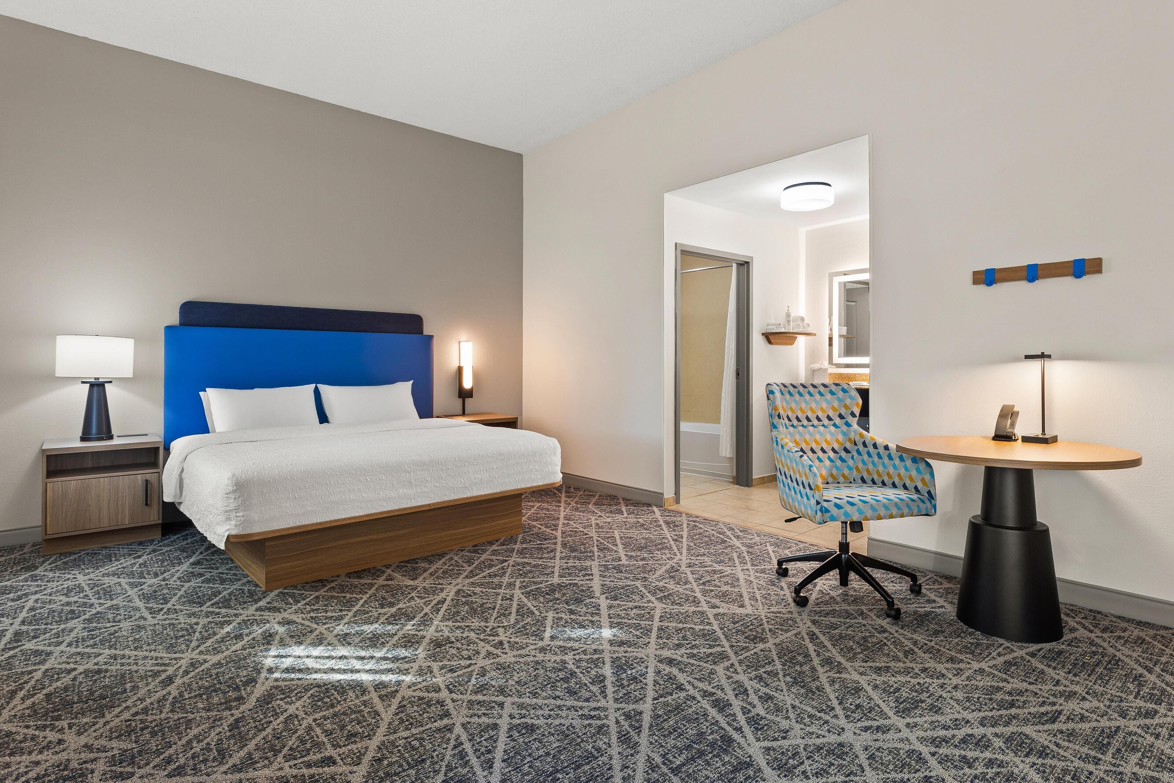 Ein Hotelzimmer mit Bett, Schreibtisch, Stuhl und einem kleinen Tisch.