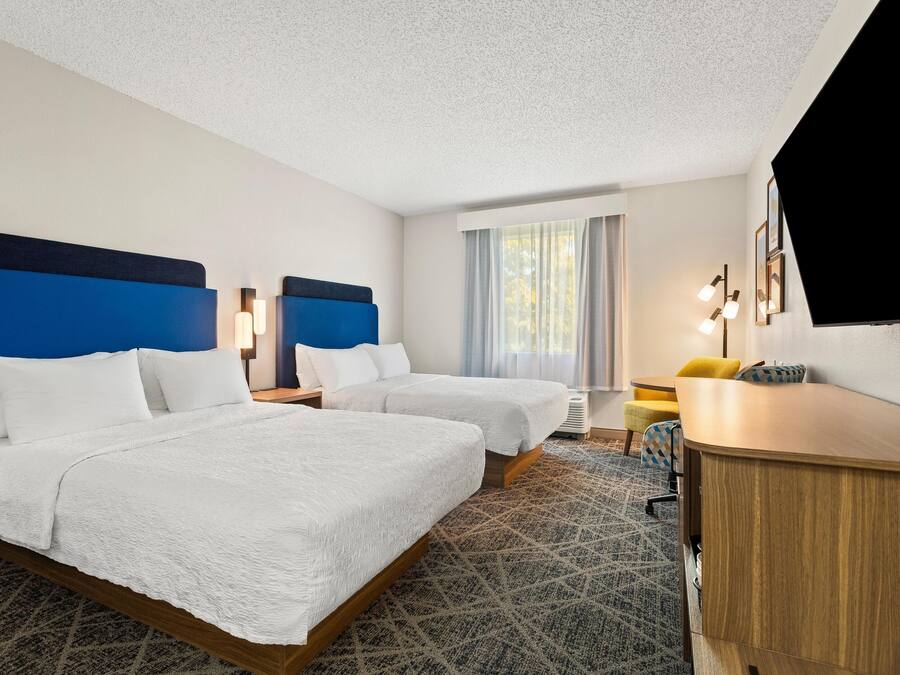 Een hotelkamer met twee bedden, een bureau en een televisie.