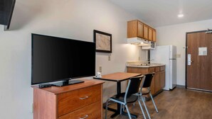 Eine kompakte Küche mit Flachbildfernseher, Holzschränken, einer Mikrowelle und einem Kühlschrank.