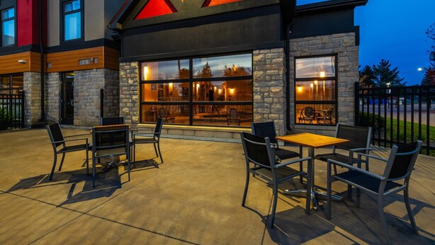 An outdoor seating area with stone walls and large windows, a fire feature, and a modern building facade. - Quality Inn and Suites Petawawa (Petawawa)