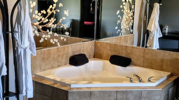 A modern bathroom with a large freestanding bathtub, a mirror, and a decorative branch with flowers.
