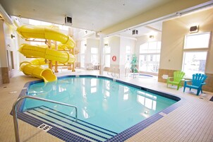 Una piscina interior con tobogán, sillas y puesto de socorrista.