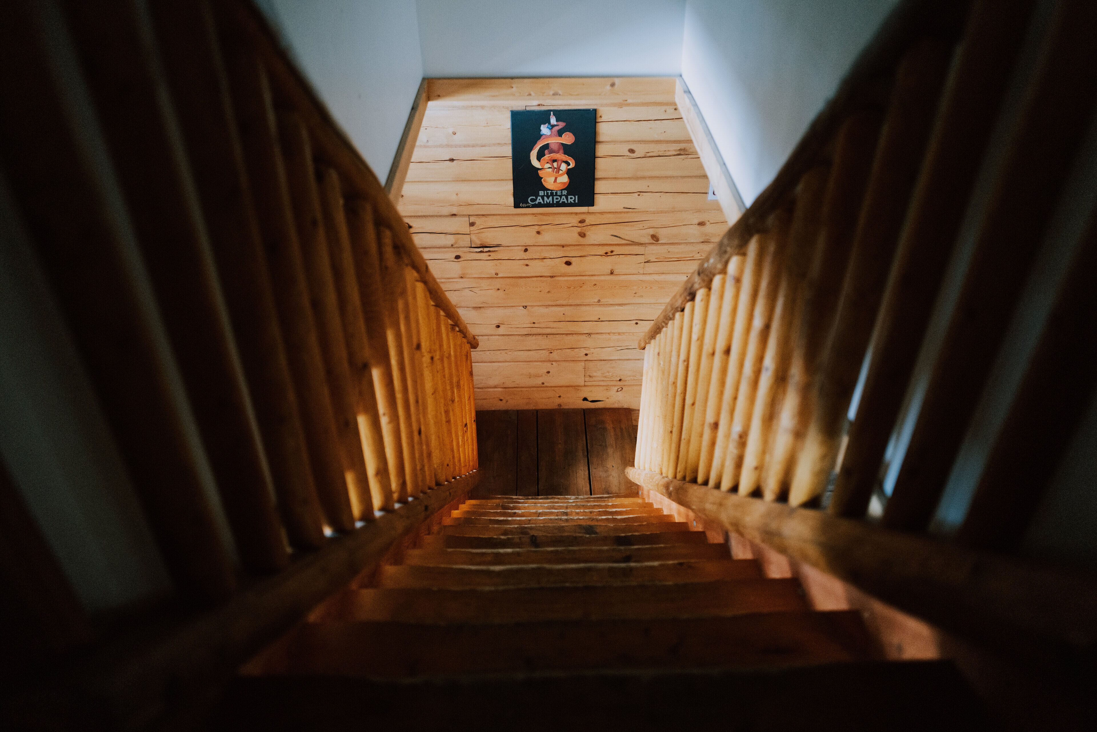 A wooden staircase with a sign at the top reading "Bitter Campari".