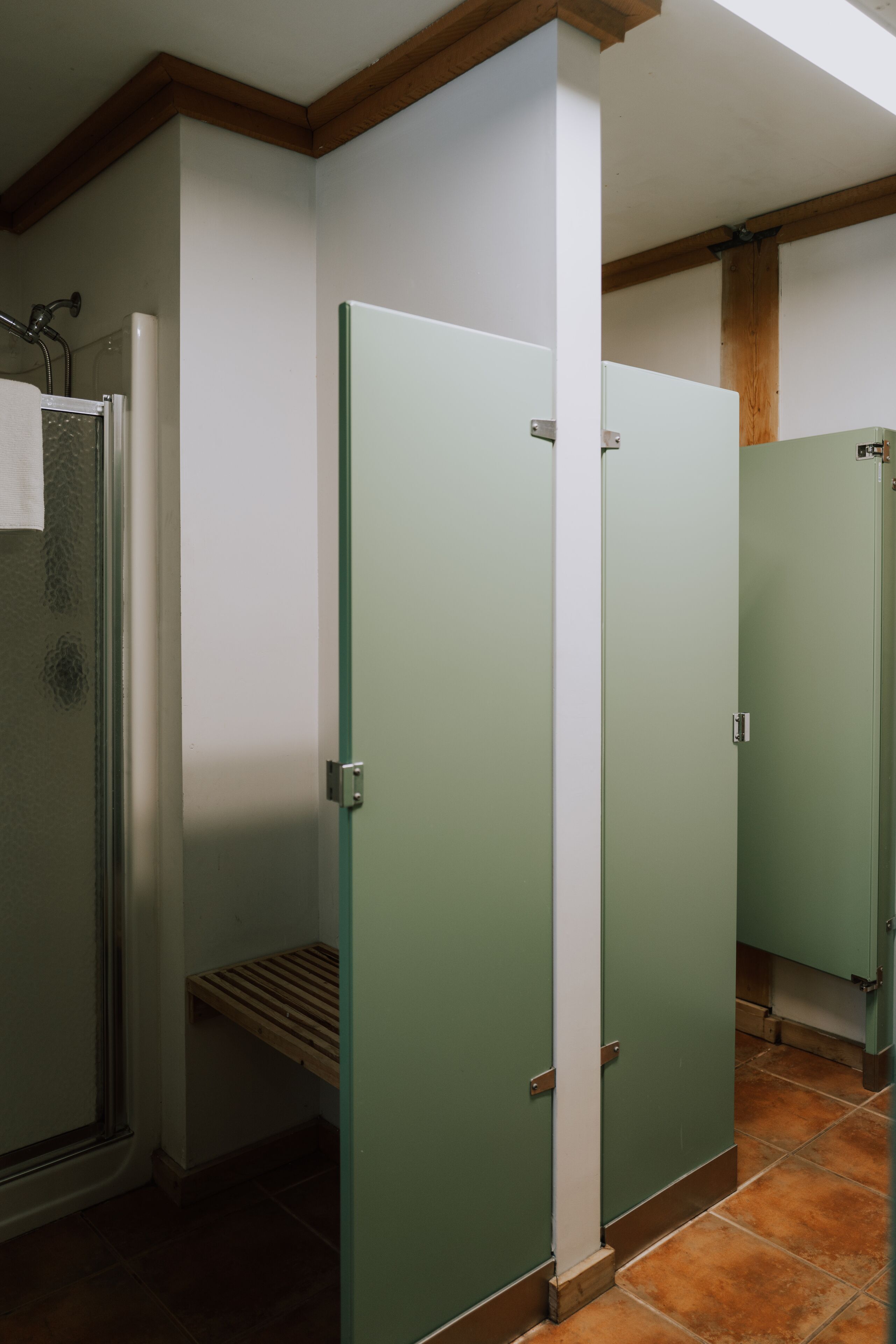 Un bagno con porte verdi, zona doccia e panca in legno.