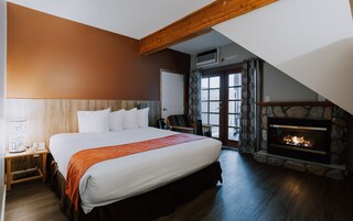 Un dormitorio con una cama grande, una chimenea de piedra y vistas al exterior a través de una puerta.