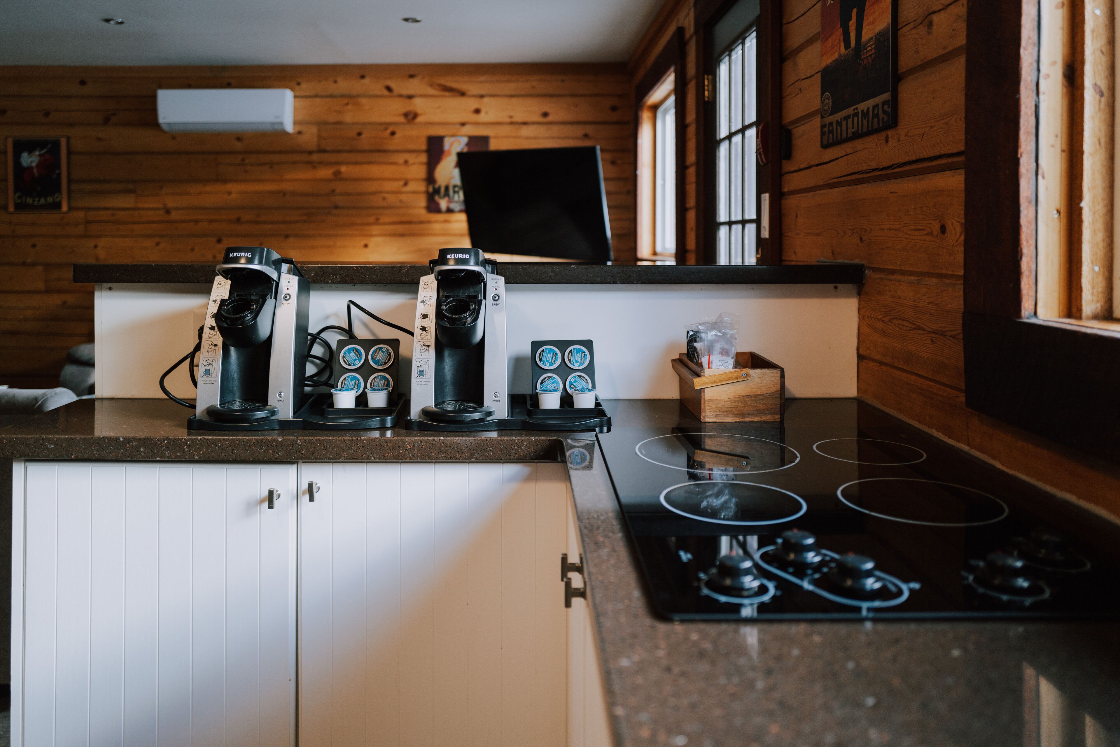 A kitchen with a stove, coffee makers, and wooden cabinets.