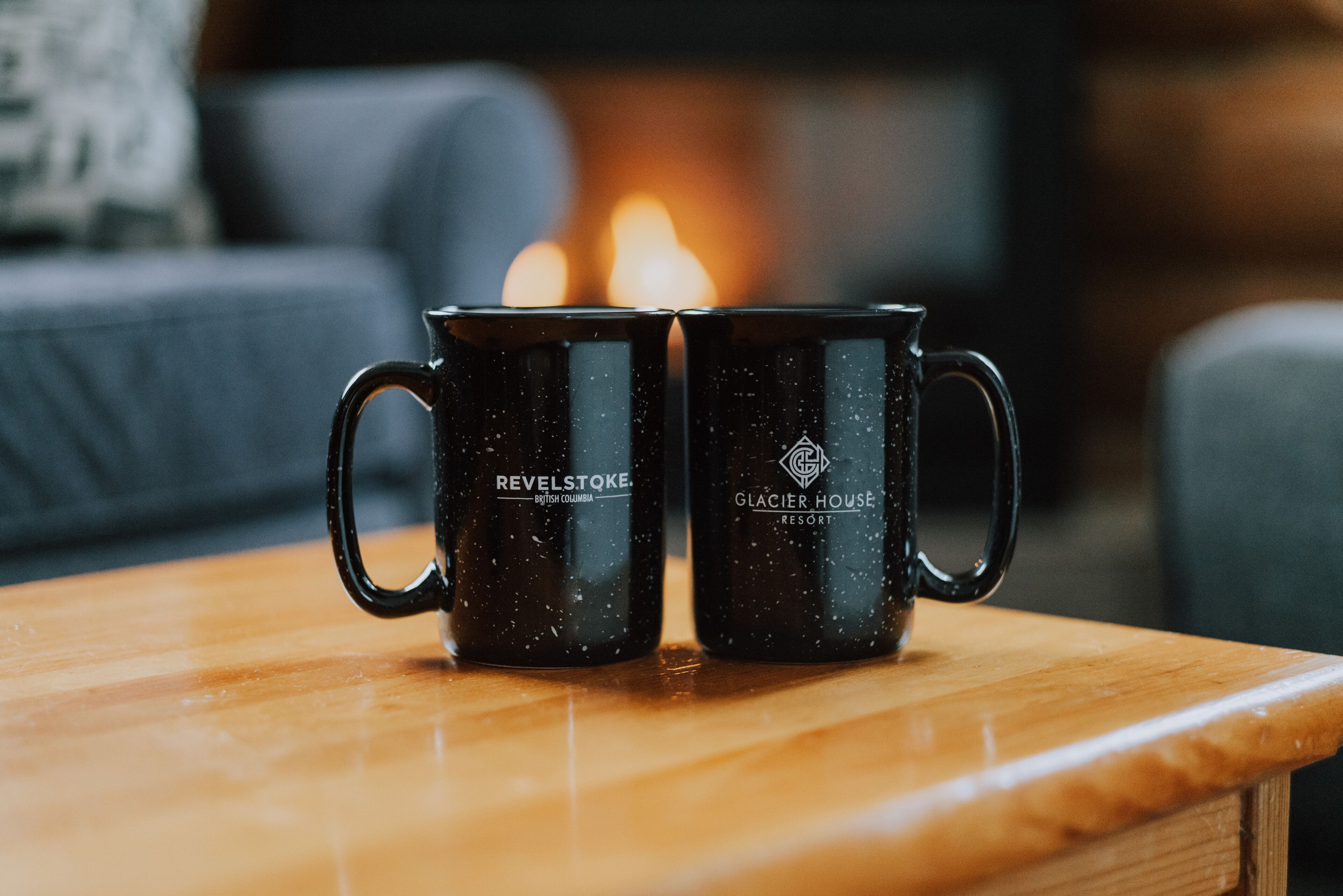 Two black mugs with inscriptions on a wooden surface.