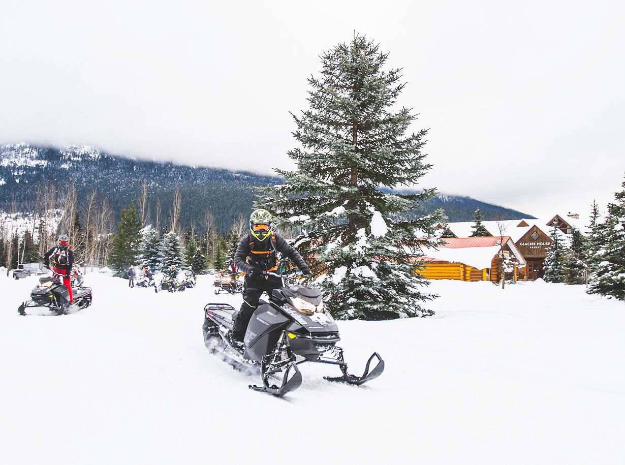 A snowmobile in a snowy landscape with a lodge in the background.