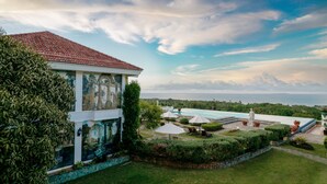 A villa with a tiled roof, a swimming pool, and a view of the sea. - The Peacock Garden (Baclayon)