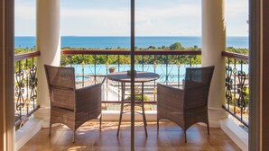 A balcony with two wicker chairs and a small table, overlooking a pool and ocean. - The Peacock Garden (Baclayon)