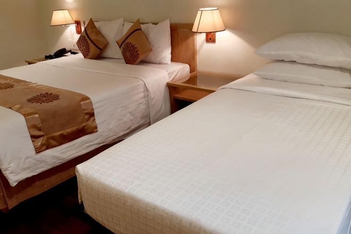Dos camas individuales con cabeceras, mesitas de noche, lámparas y almohadas decorativas.