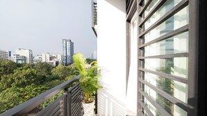 A balcony with a potted plant, a cityscape view, and a modern building facade. - Vien Dong Hotel (Ho Chi Minh City)