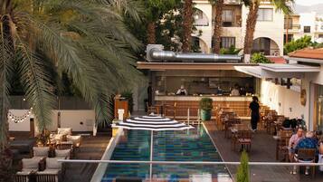 A poolside area with lounge chairs, a bar, and a view of the cityscape.