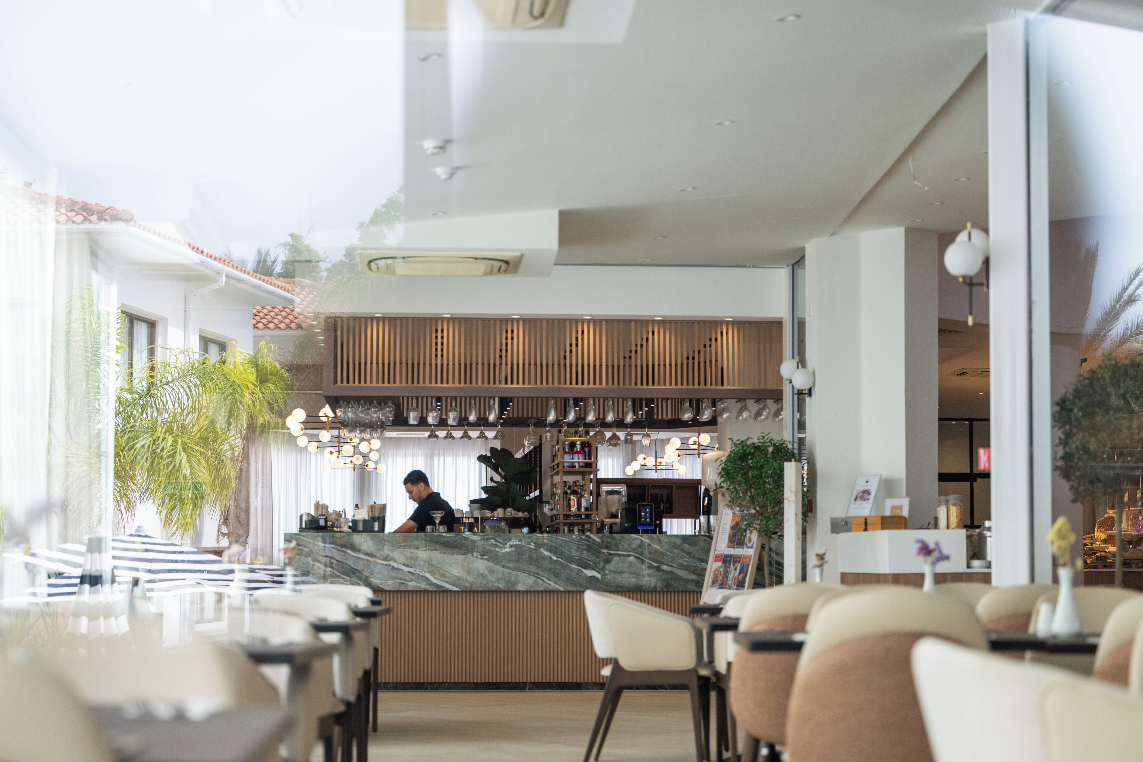 A modern restaurant with a marble counter, wooden paneling, and a bar area.