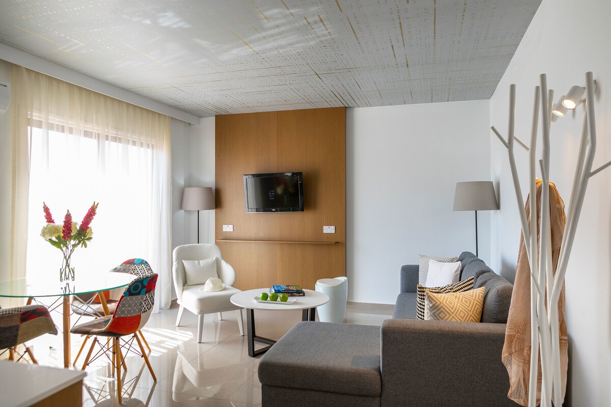 Una sala de estar moderna con un televisor de pantalla plana, una mesa de comedor de vidrio y un sofá.