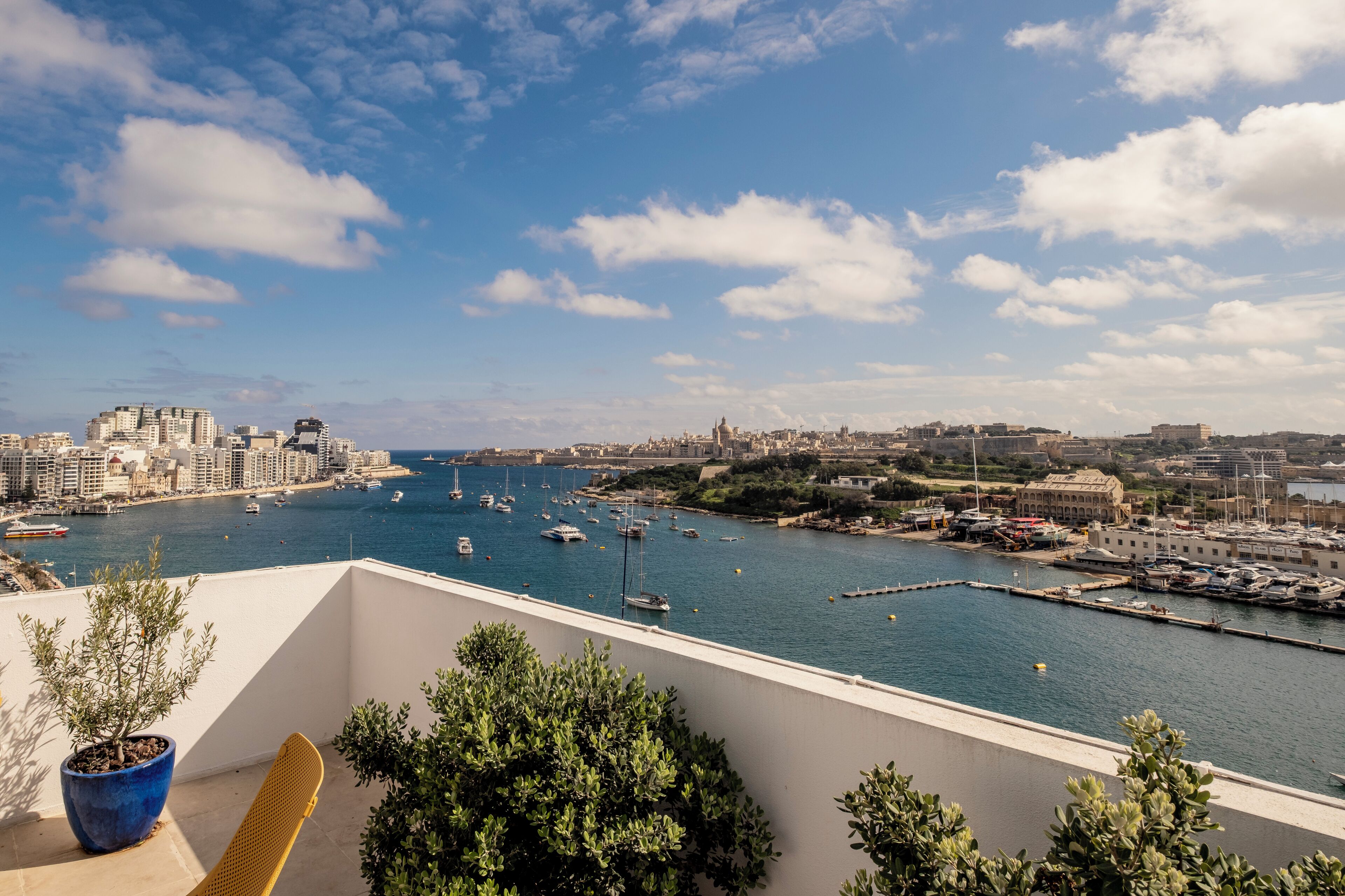 Un balcón con vistas a un puerto deportivo y al paisaje urbano.