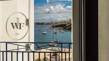 A view from a balcony overlooking a marina with boats, a dome-shaped building, and a circular emblem on the wall.