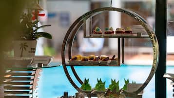 A dessert display with various sweets and a pool view in the background.