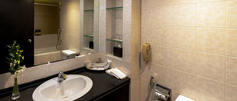 A modern bathroom with a white sink, a glass shower enclosure, and a large mirror.