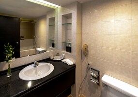 Ein modernes Badezimmer mit einem weißen Waschbecken, einer Duschkabine aus Glas und einem großen Spiegel.