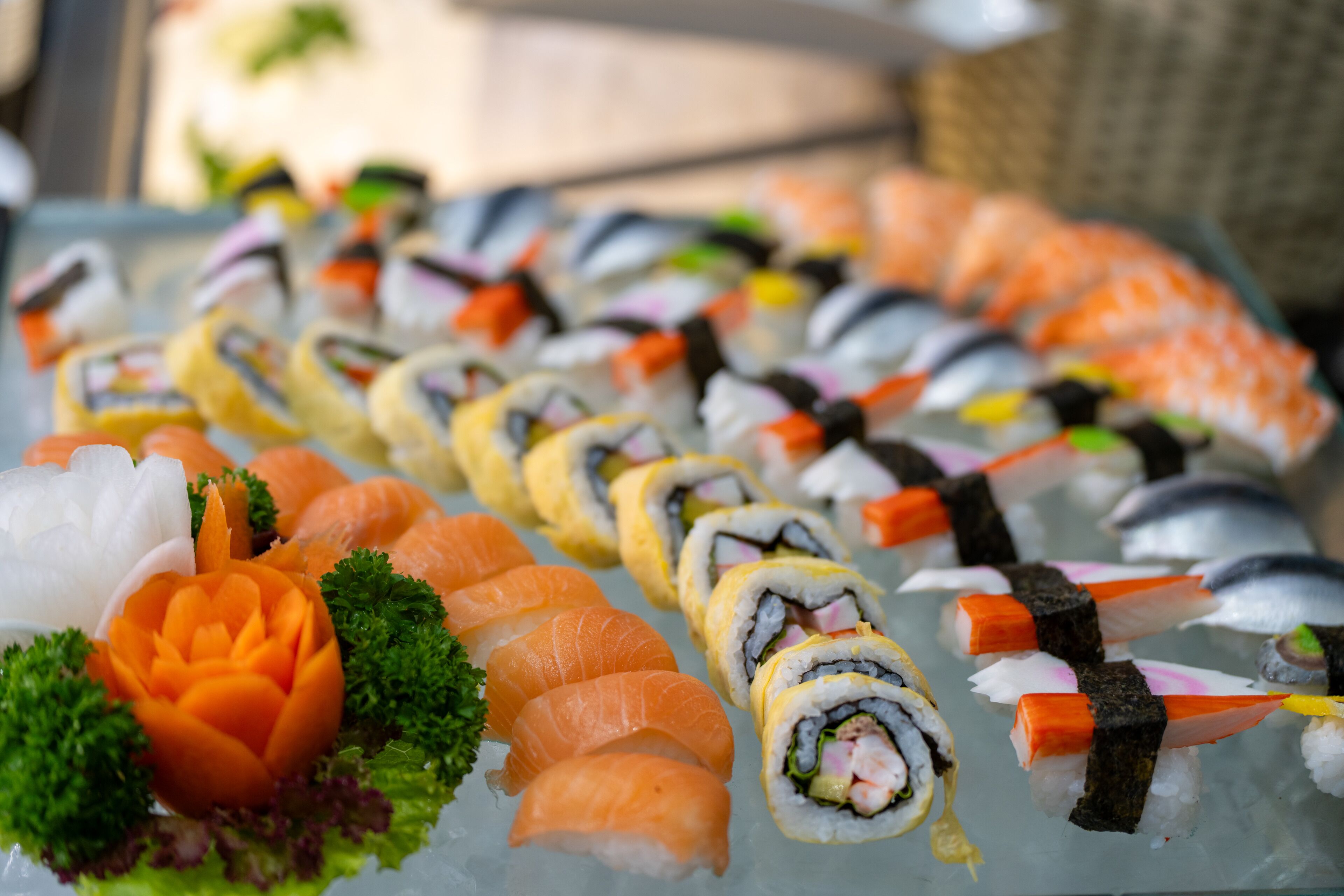 A variety of sushi rolls and sashimi on a glass tray.