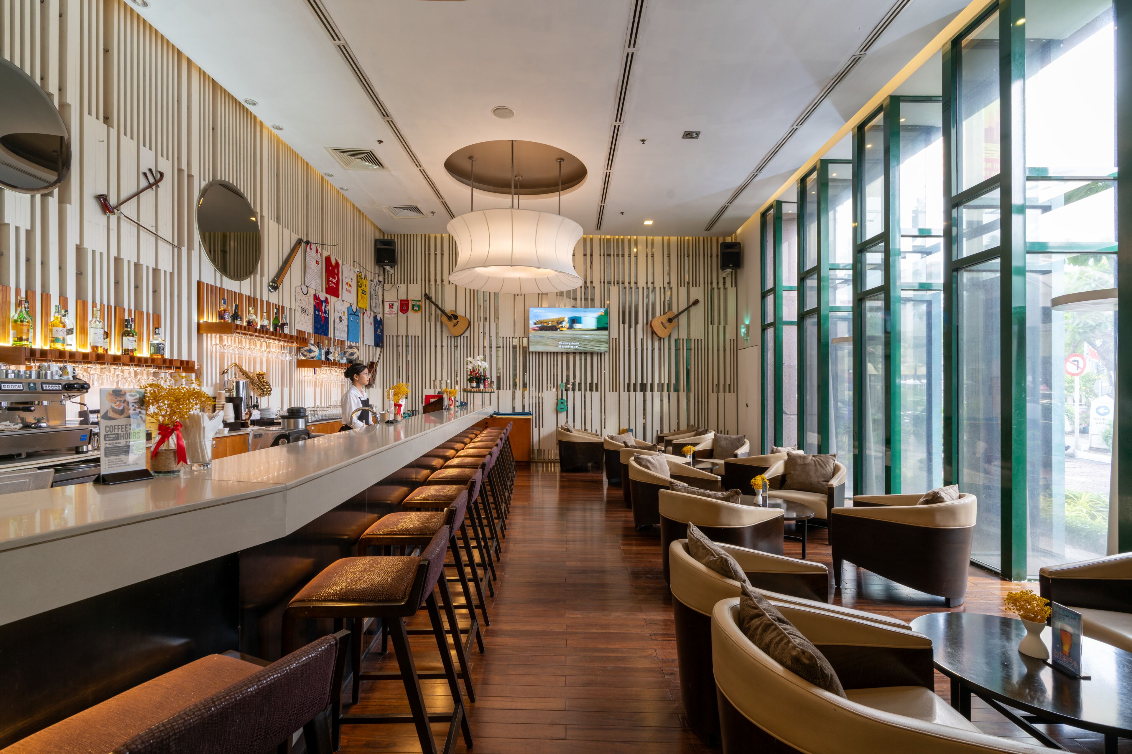 Een moderne bar met een lange toonbank, verschillende krukken en een zithoek met banken en tafels.