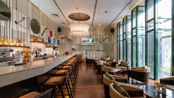 Een moderne bar met een lange toonbank, verschillende krukken en een zithoek met banken en tafels.