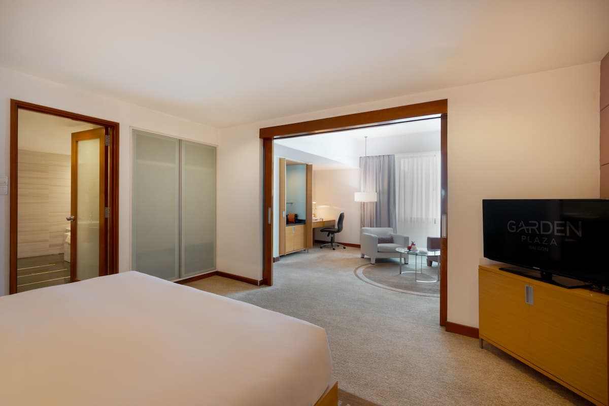 Una habitación de hotel con cama, televisión, escritorio y silla, y vistas a un balcón.