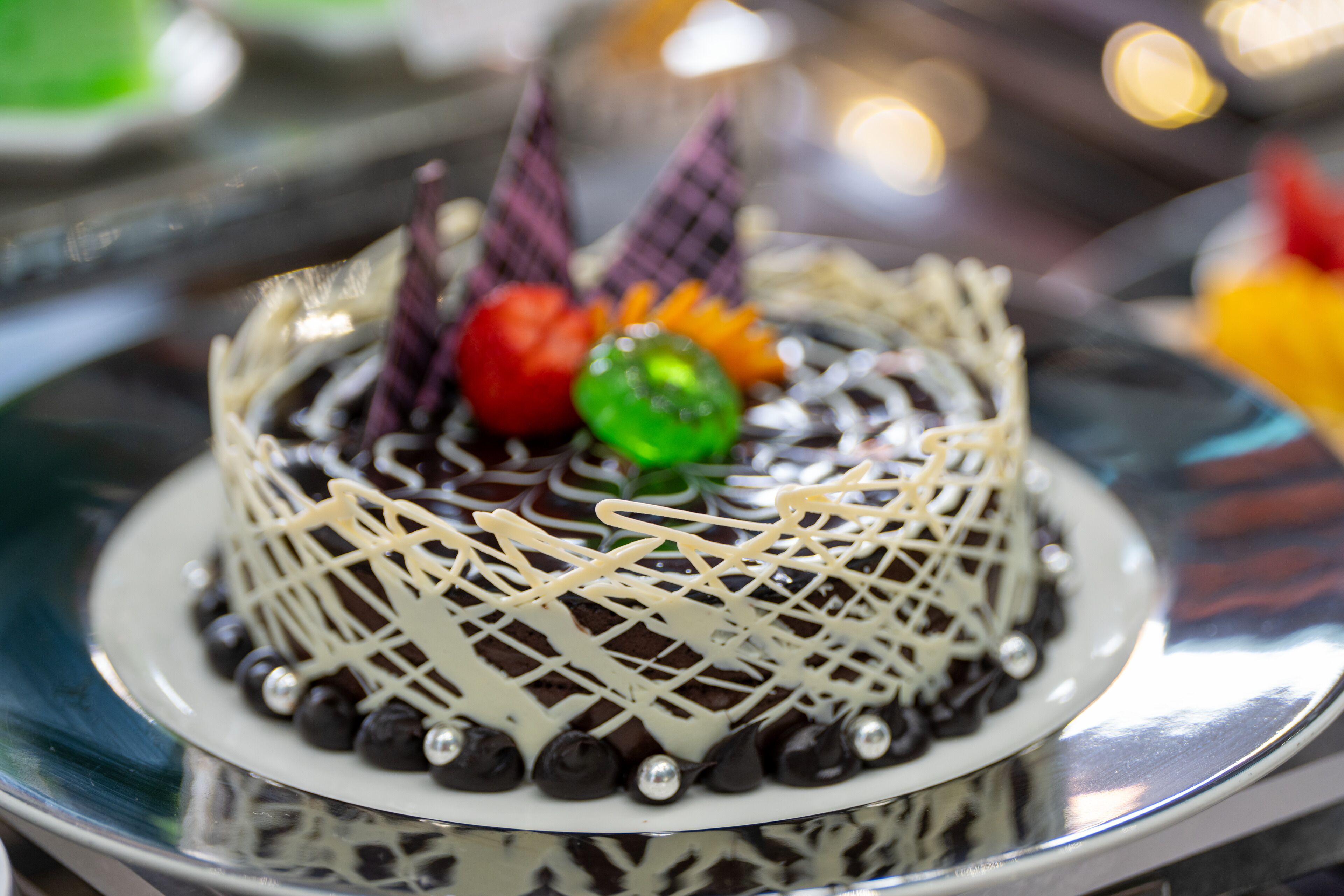 Taart met chocolade en witte glazuur, versierd met chocoladebolletjes en een ruitpatroon.