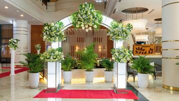 A hotel lobby with a red carpet, white columns, and floral decorations.