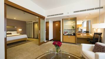 A hotel room with a bed, a sitting area with a coffee table, and a desk with a chair.