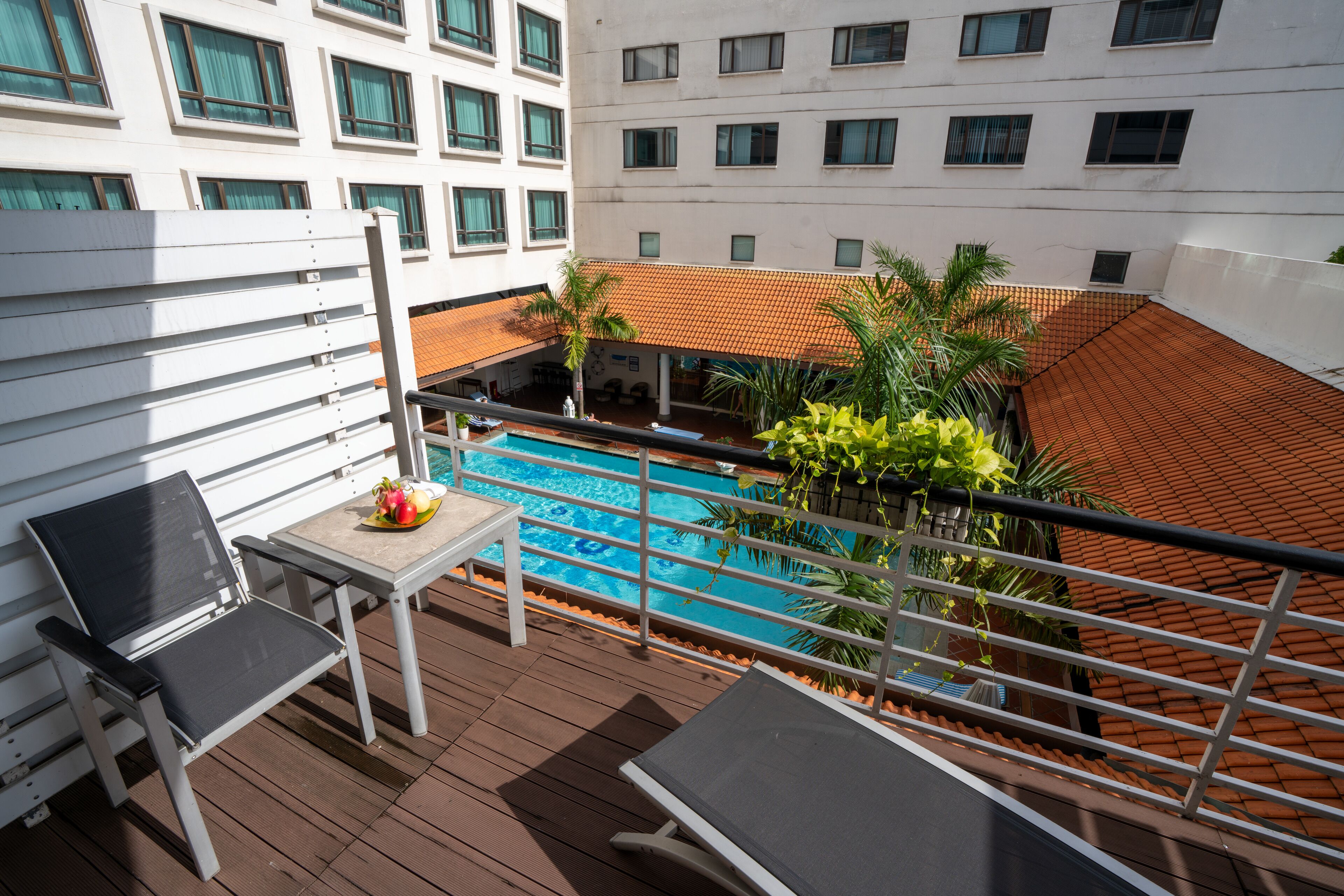Un balcone con piscina, sedie a sdraio e un tavolo pieno di frutta.