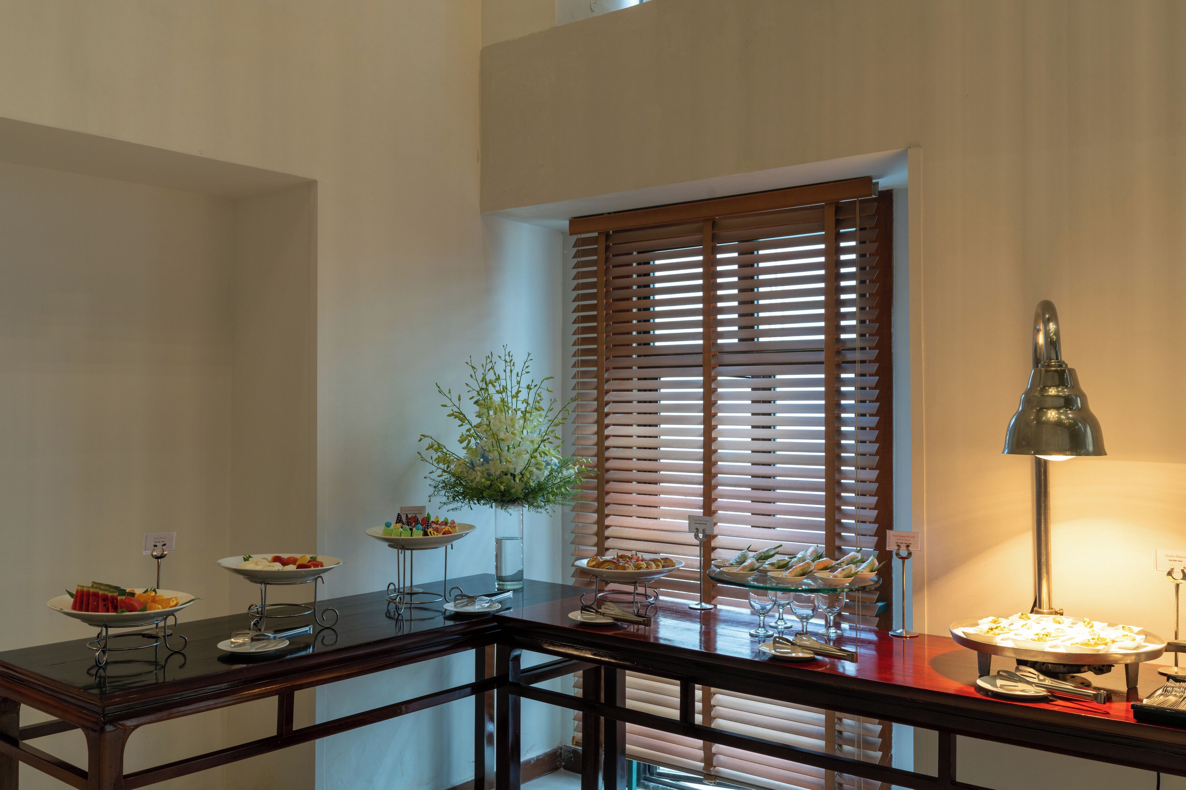 Une table de buffet avec divers plats, un vase de fleurs et une lampe.