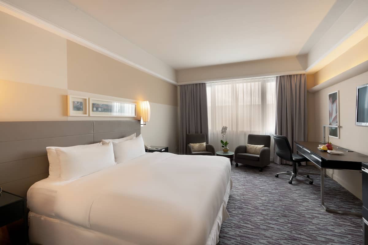 Una habitación de hotel con una cama grande, un escritorio, una silla y una pequeña mesa.