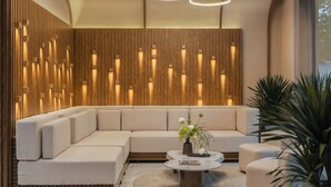 Un salon moderne avec un canapé d’angle, une table basse ronde et un mur décoratif en bois doté d’un éclairage intégré.