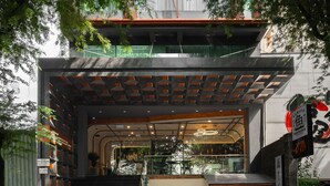 Un bâtiment moderne avec un escalier menant à l’entrée, une enseigne et une vue sur l’intérieur grâce à de grandes fenêtres.