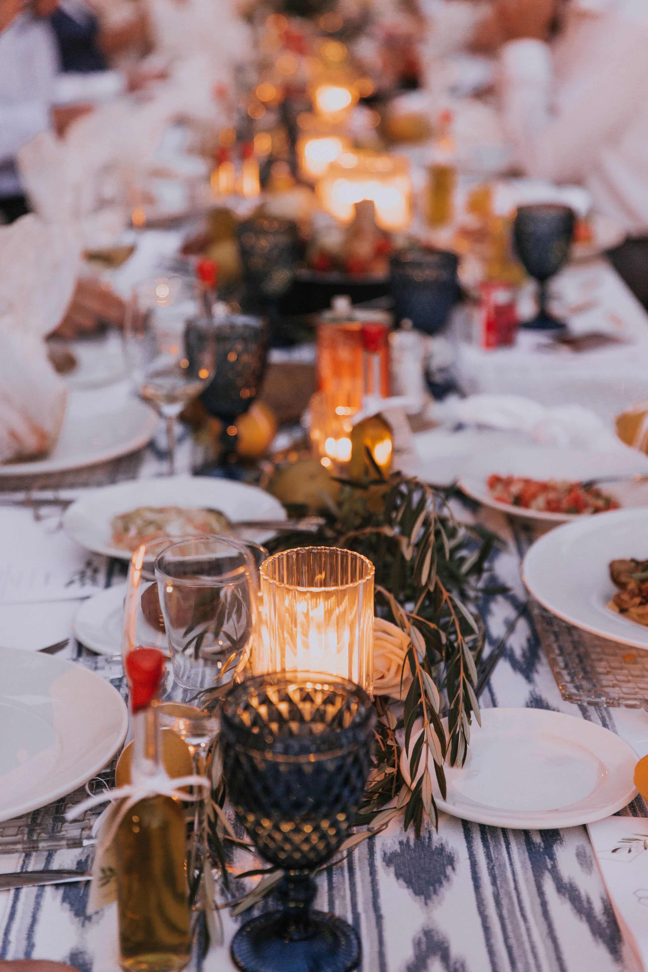 Una mesa preparada para una comida con velas, platos y copas.
