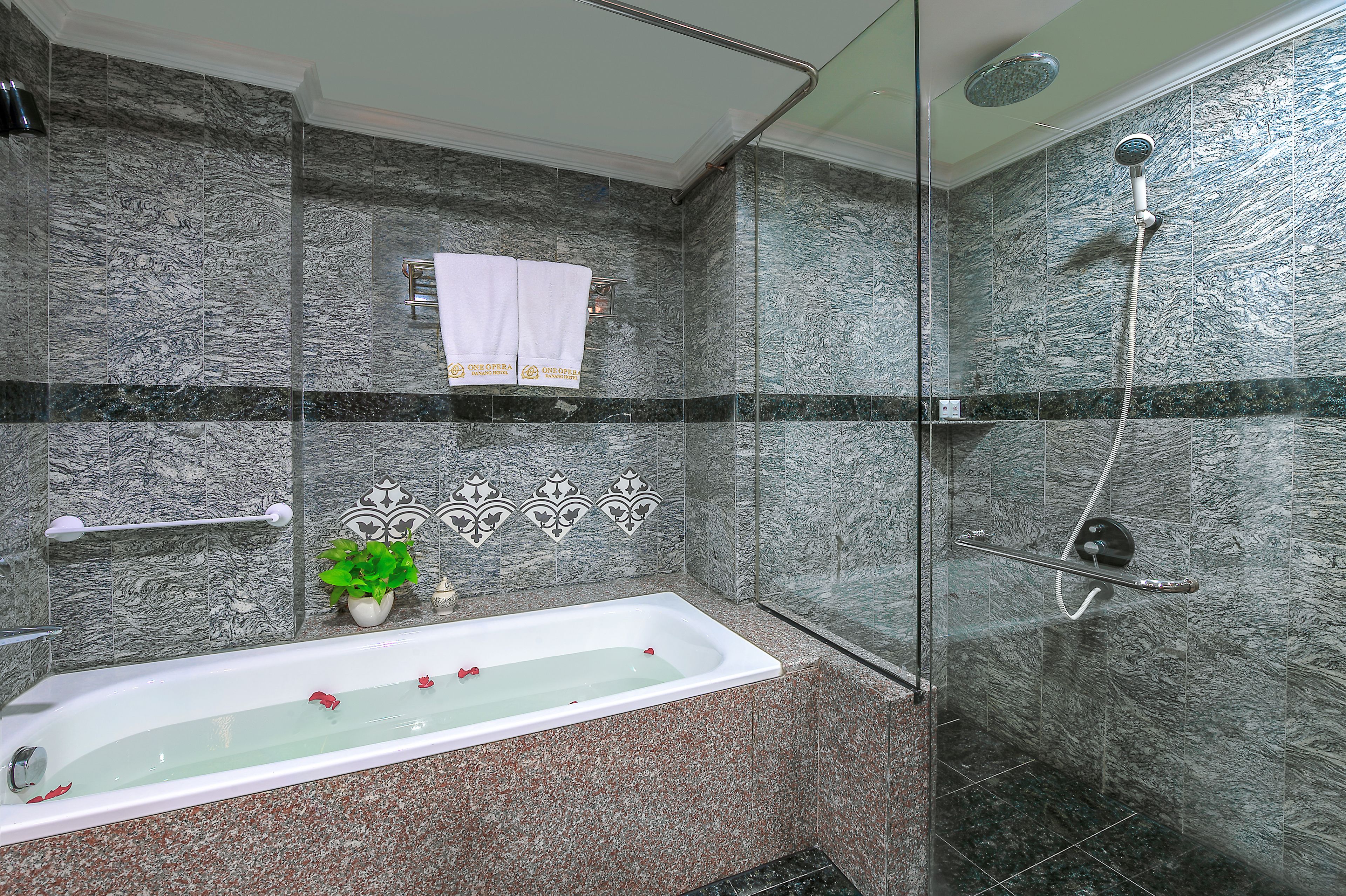 Ein Badezimmer mit Badewanne, Dusche und Marmorwänden.