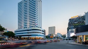 A modern high-rise hotel with a distinctive yellow crescent moon logo, a curved facade, and a rooftop garden. - Muong Thanh Luxury Song Han Hotel (Da Nang)